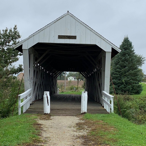 It features a timber Town Lattice truss design, a hallmark of 19th-century American wooden bridge engineering, known for both strength and aesthetic charm. 