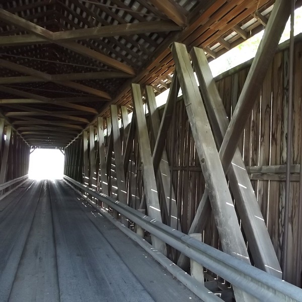 The bridge is a covered Howe truss, built by the Smith Bridge Company in 1877. 