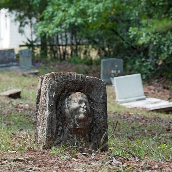 Located a few graves away is another “death mask” headstone. It is a rough-hewn marker that contains a woman’s face that bears the words Angel Ezella Nettles and “Sis Dollie” in raised letters. 