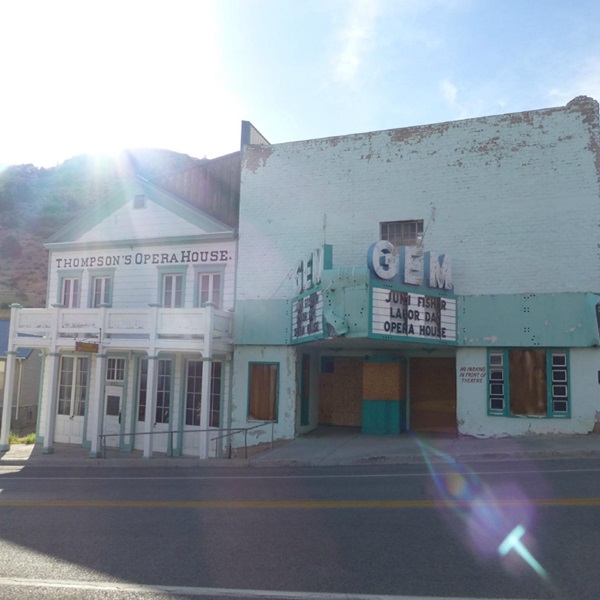 The building is a wood-frame structure designed in a classic revival style combined with early pioneer board construction and features a two-story layout with a front-facing gable. 