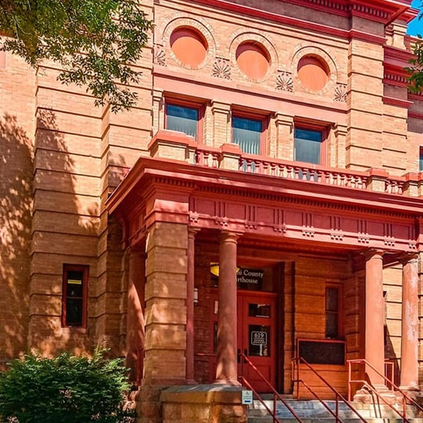 The courthouse is designed in the Richardsonian Romanesque style, characterized by its use of stone, rounded arches, and a prominent clock tower. 