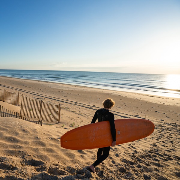 The beach has a sandy bottom, and the sandbars can shift with the tides and storms, creating varying wave shapes and sizes. 